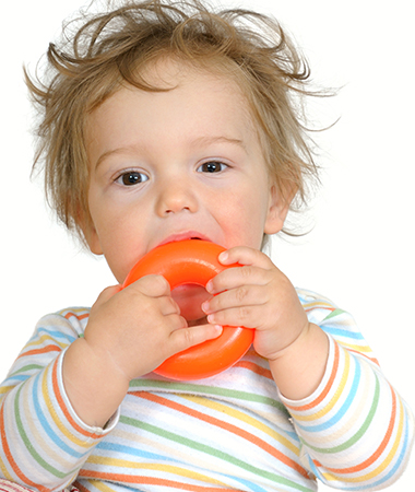 A toddler chewing on a baby toy