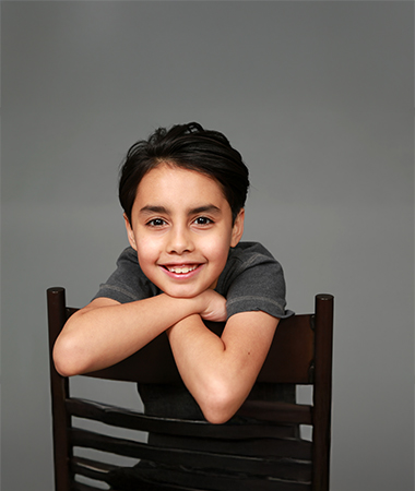 A happy child sitting reverse on a chair