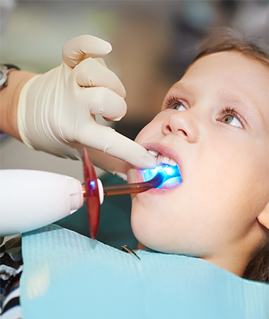 A child in a dental chair with dental instrument in his mouth